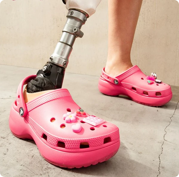 Pink crocs shoes are worn by someone with a prosthetic lower limb