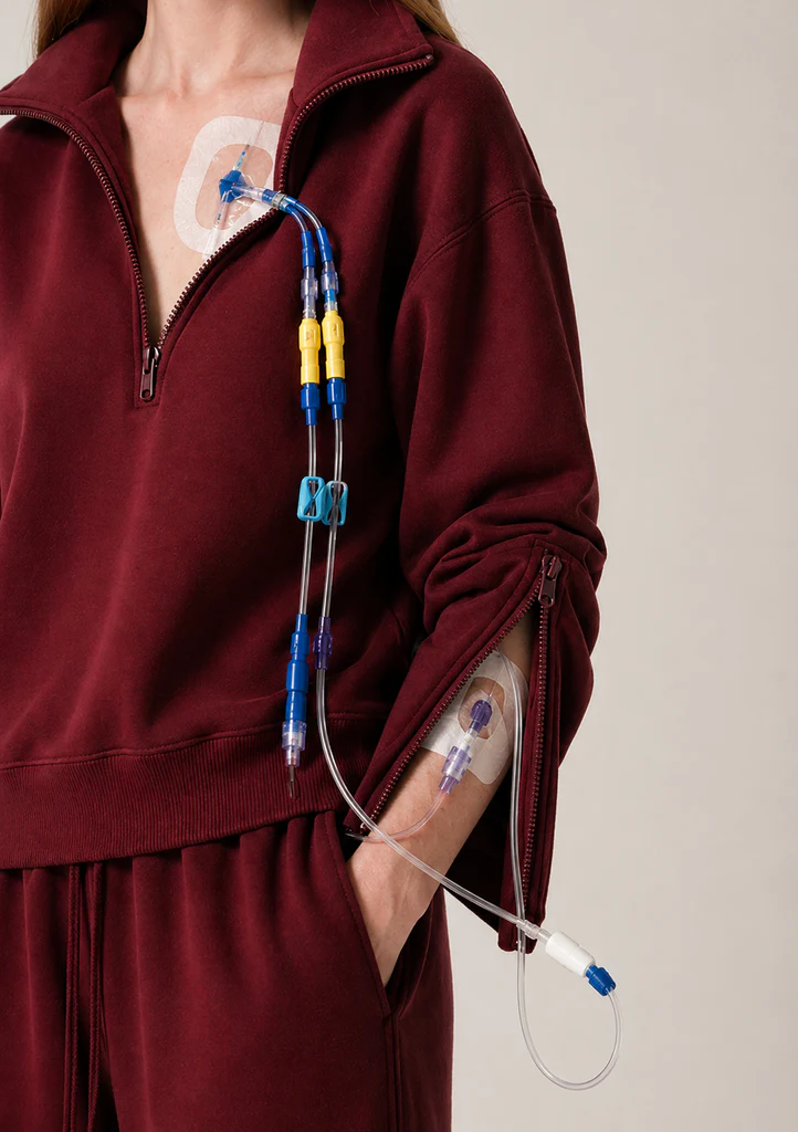 Woman wears burgundy tracksuit showing chemotherapy tubes