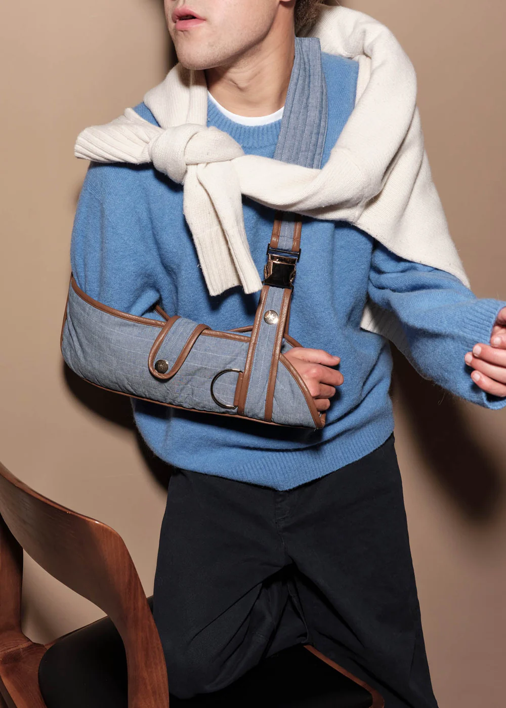 Man stands wearing pale blue sling with tan brown detail