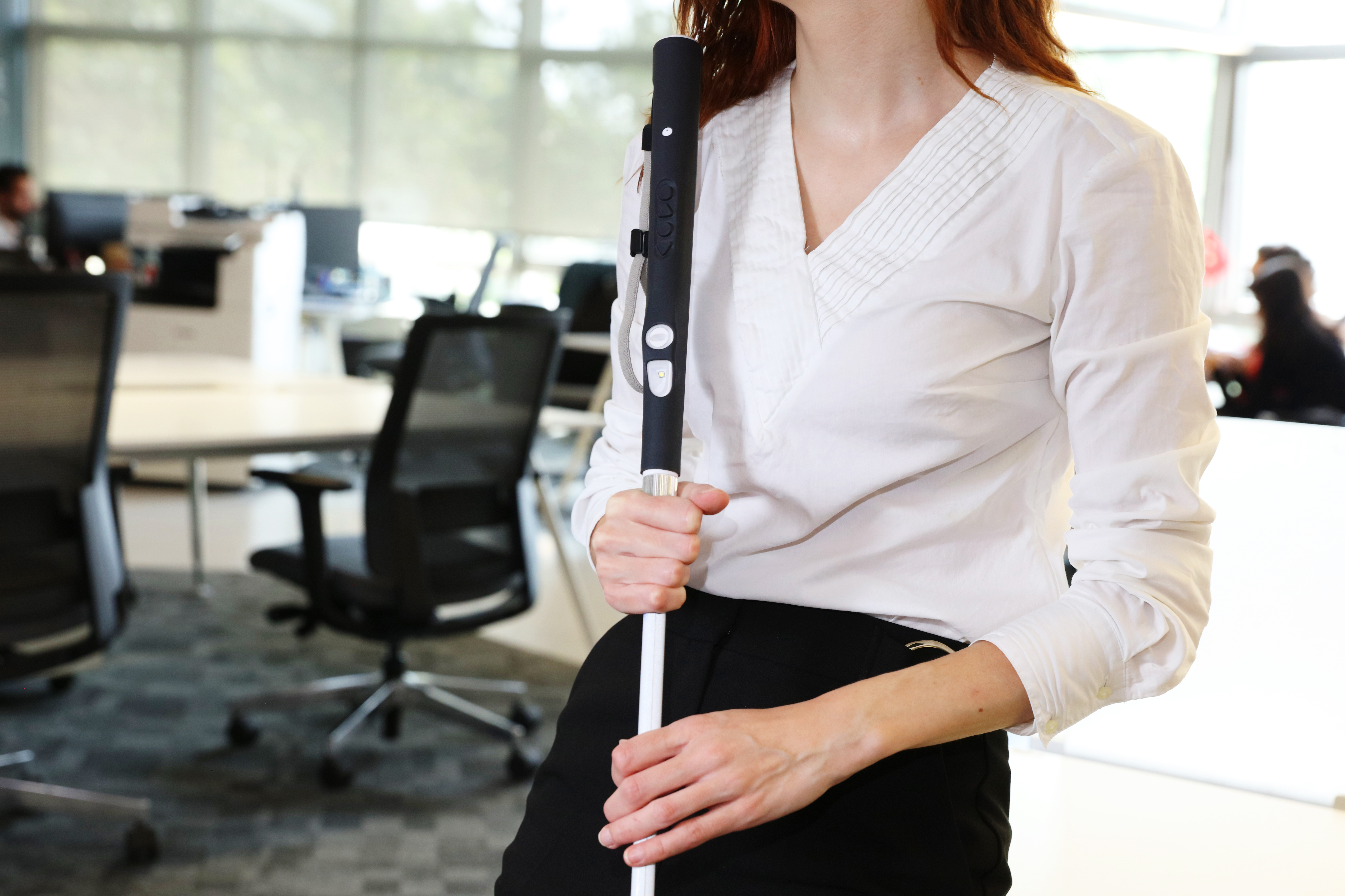 A woman holds WeWalk smart cane on the office