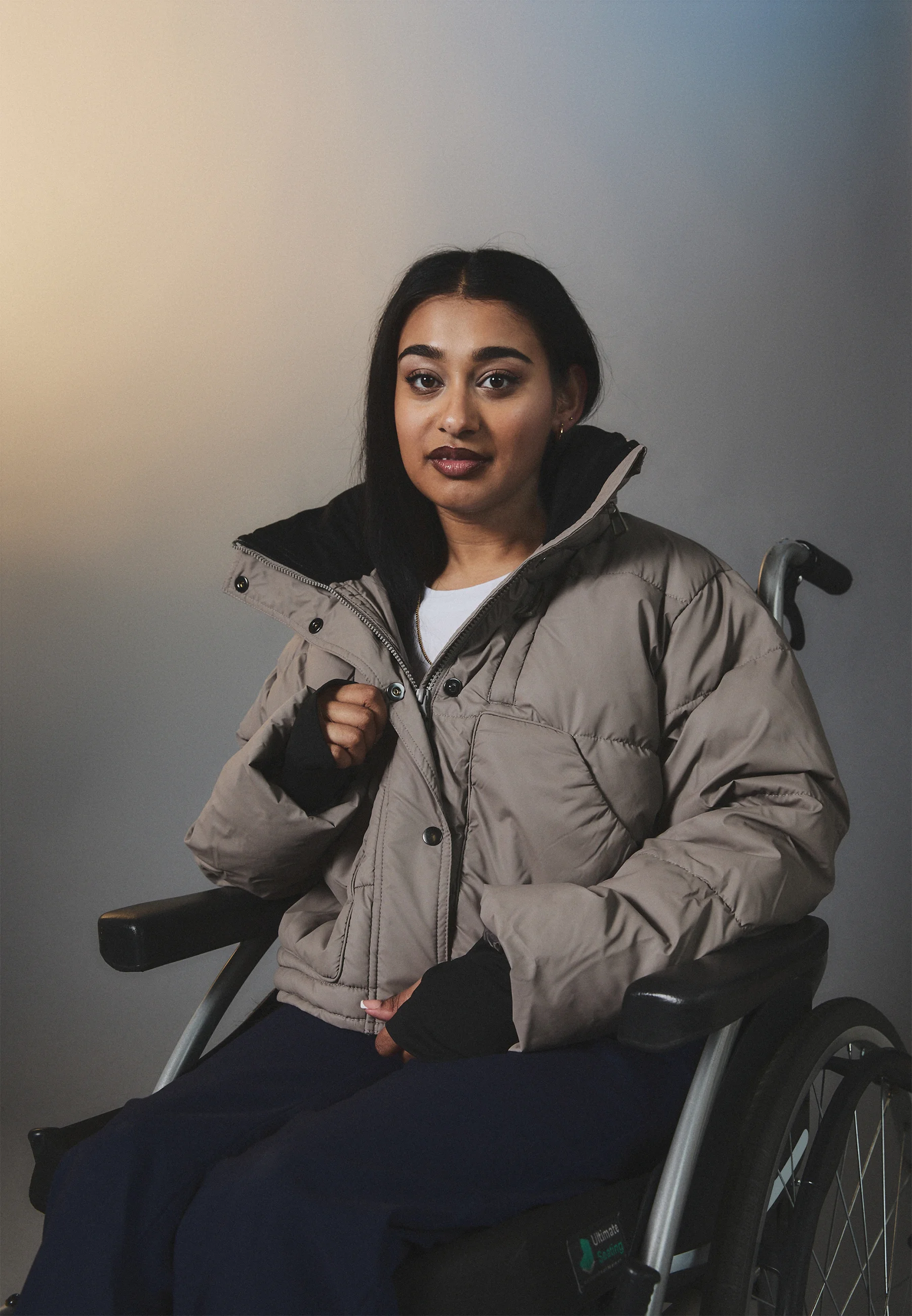 Woman in a wheelchair wears a beige puffer jacker