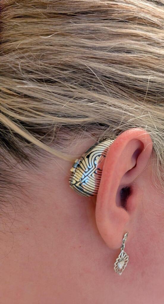 Close up photo shows woman wearing a gold and black bespoke design