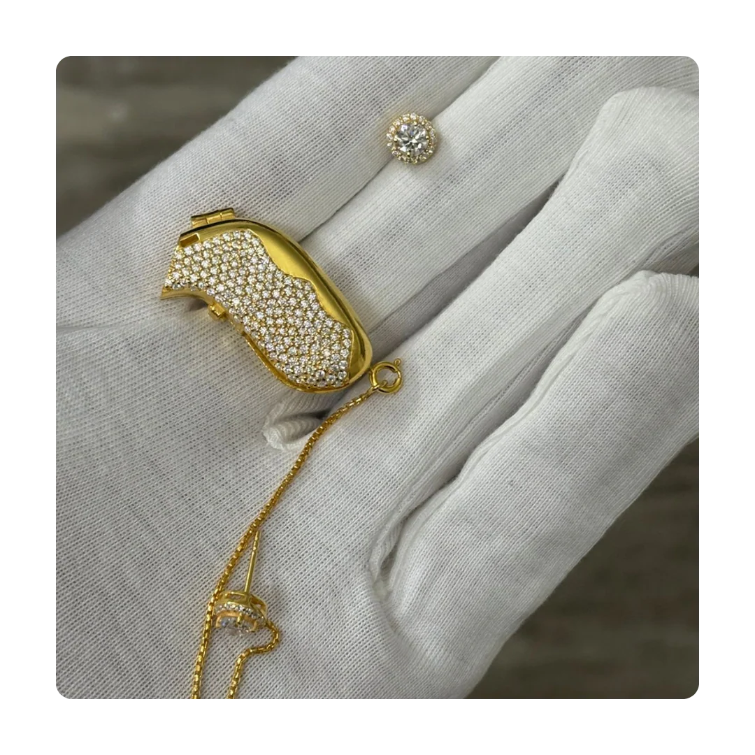 A gloved palm shows gold and diamante set with earrings and gold chain