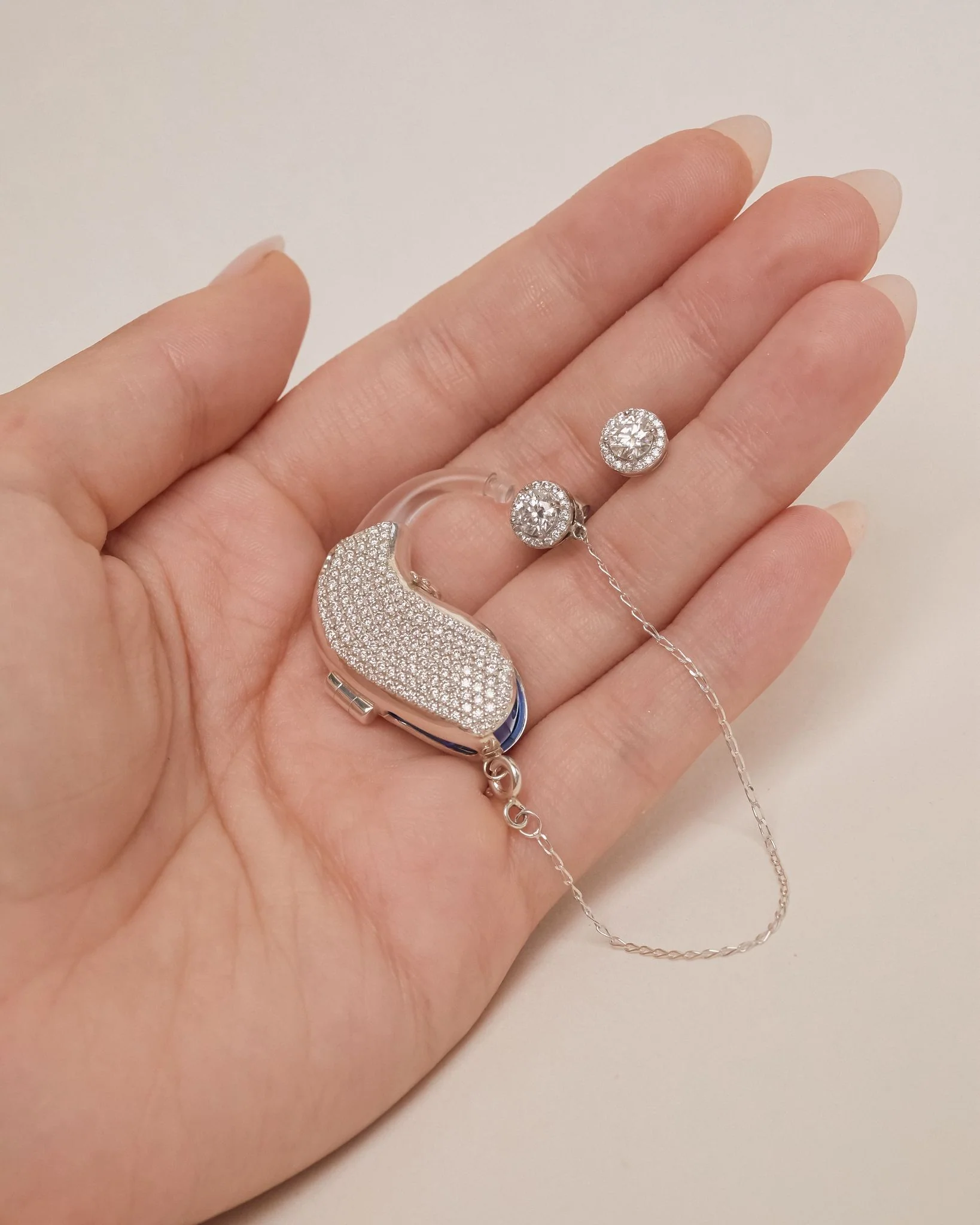 Diamante design with chain and round earrings sits in the palm of a hand