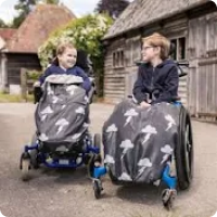 two boys in wheelchairs smiling at each other with the storm design wheelchair cover