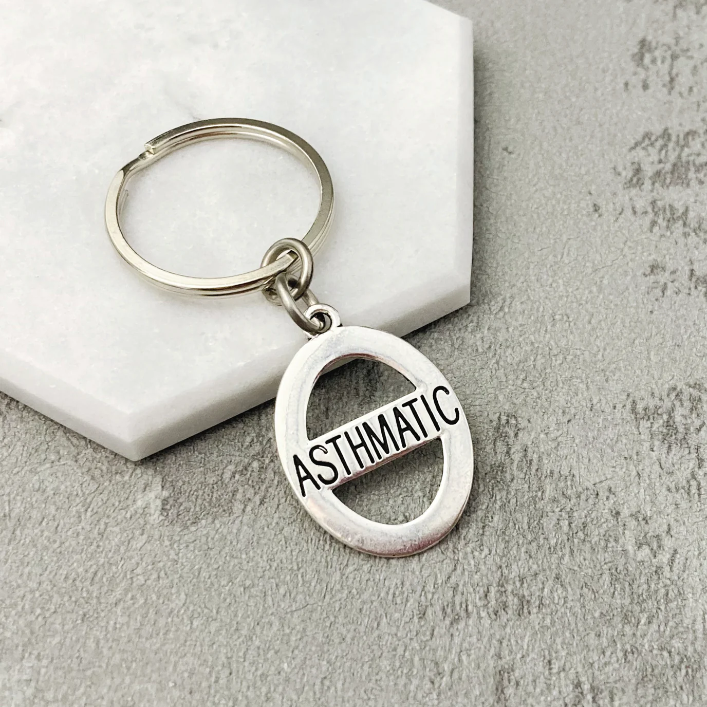 Silver round keyring with Asthmatic written in black