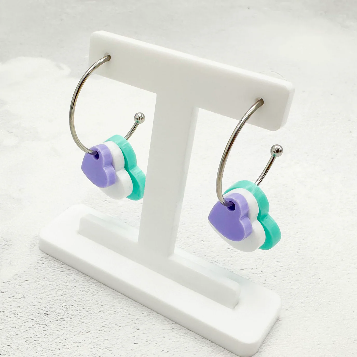 Purple white and green layered heart earrings to indicate genderqueer