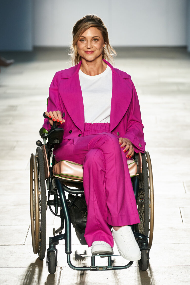 Woman using a wheelchair wears fuschia pink trouser suit