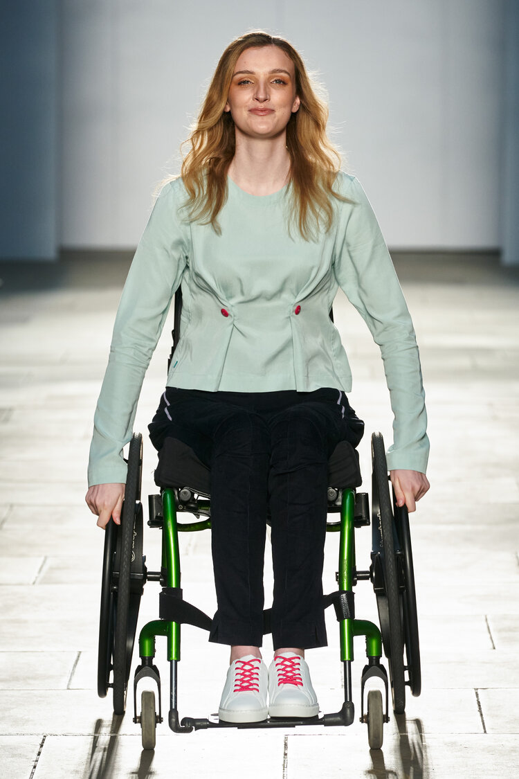 Woman using a wheelchair wears mint green jacket with button feature at waist
