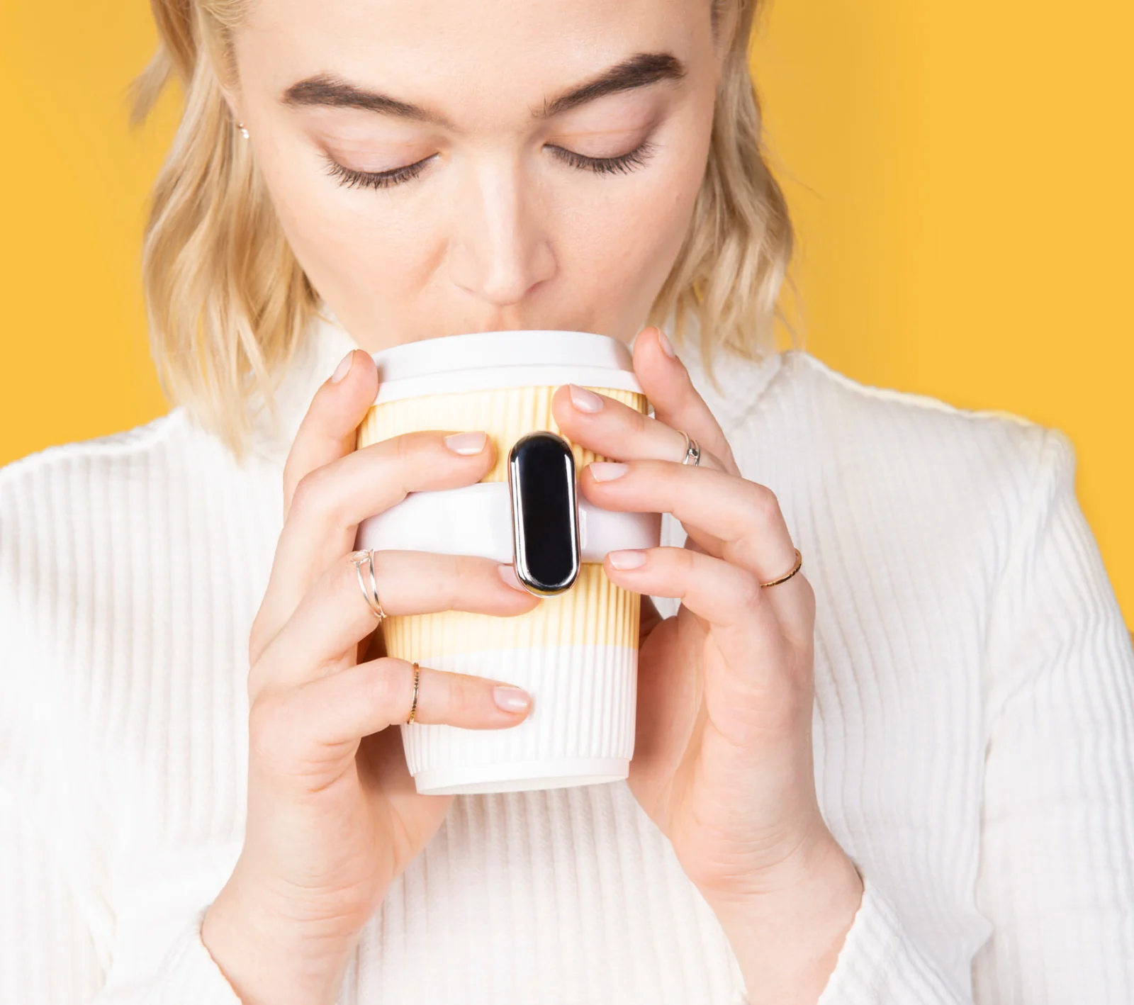 Woman shown drinking with cup holder fitted to a white cup
