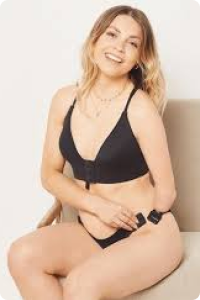 Smiling blonde woman show front fastening black bra whilst seated