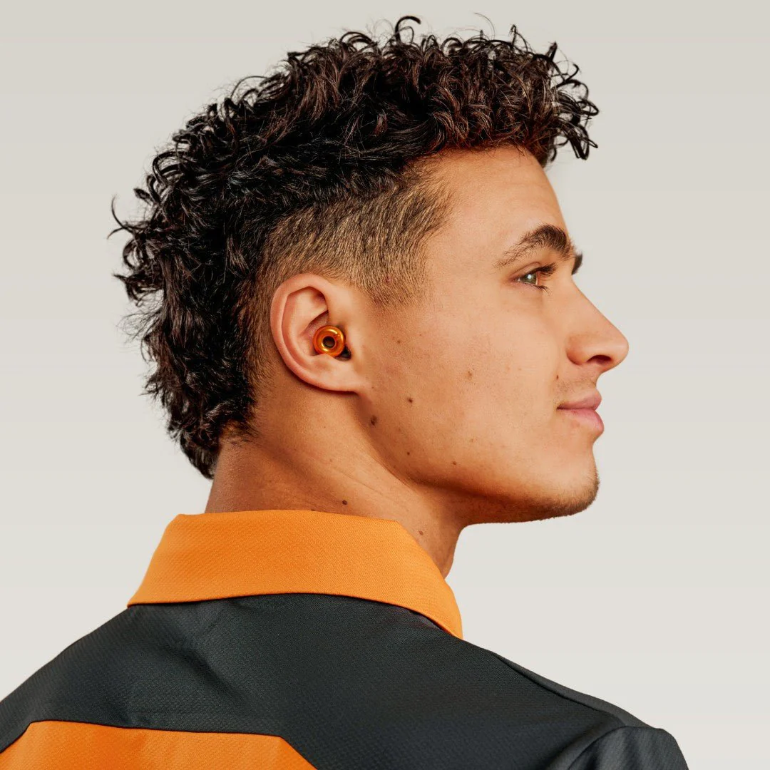 Man wears Maclaren earplugs in orange 'Maclaren Papaya'