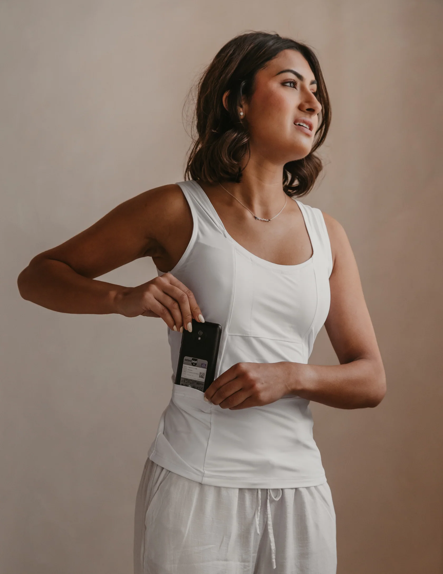 `Woman wears white tank top with medical advice in side pocket.