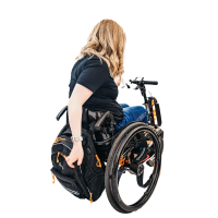 Woman demonstrates use of ease of opening a bag on the back of her wheelchair