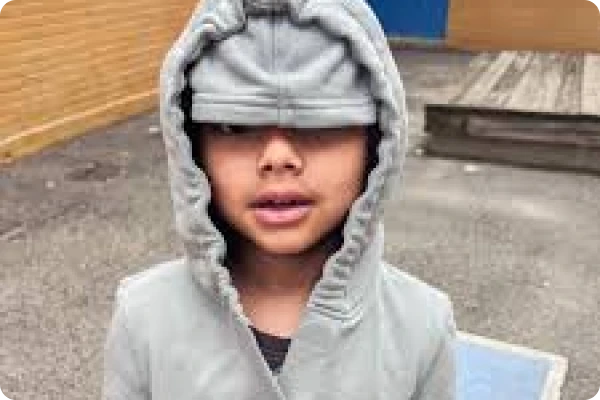 Boy wears grey sound reducing hoodie with inner eye mask