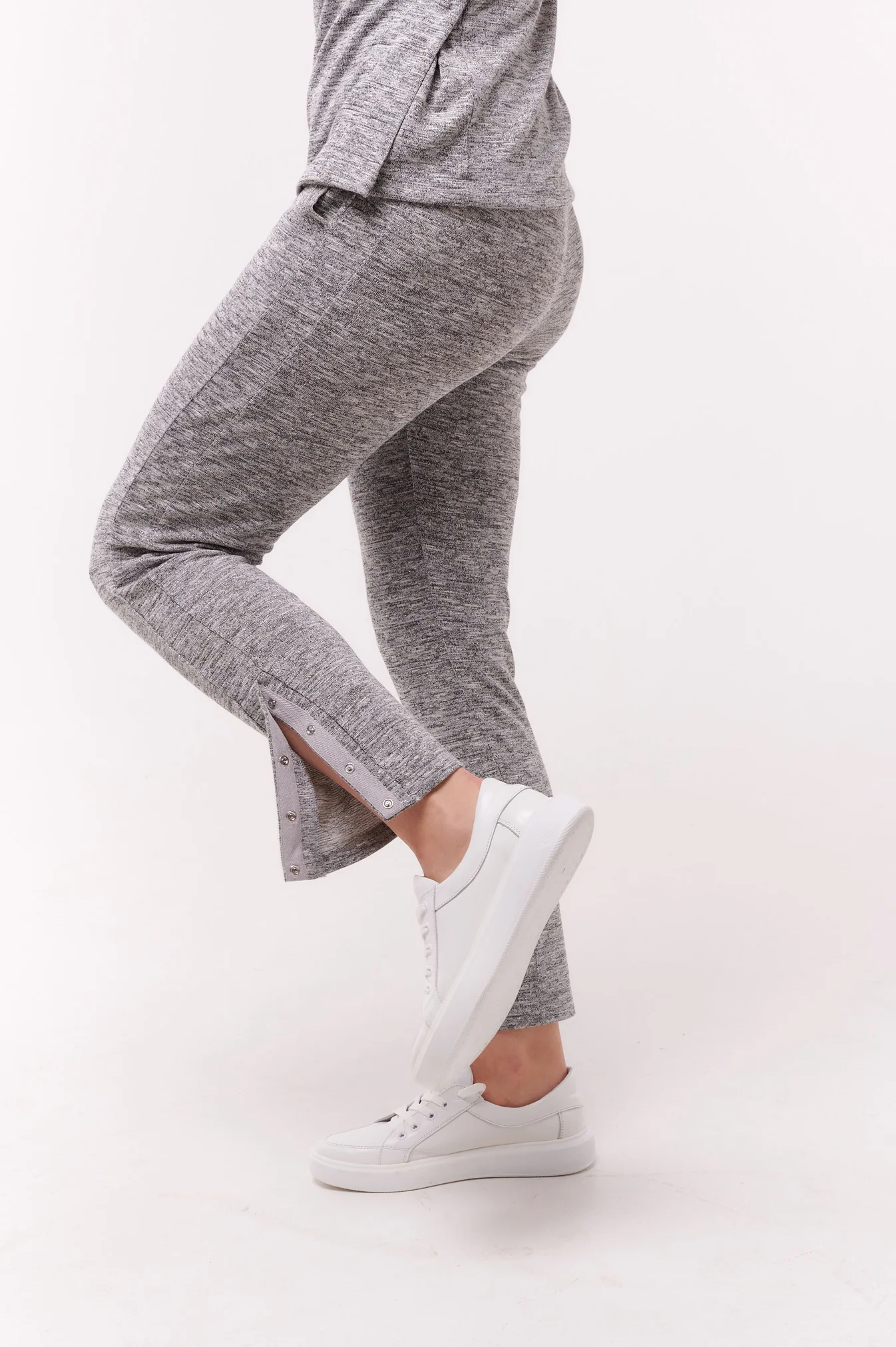 Woman wears grey trousers with ankle opening