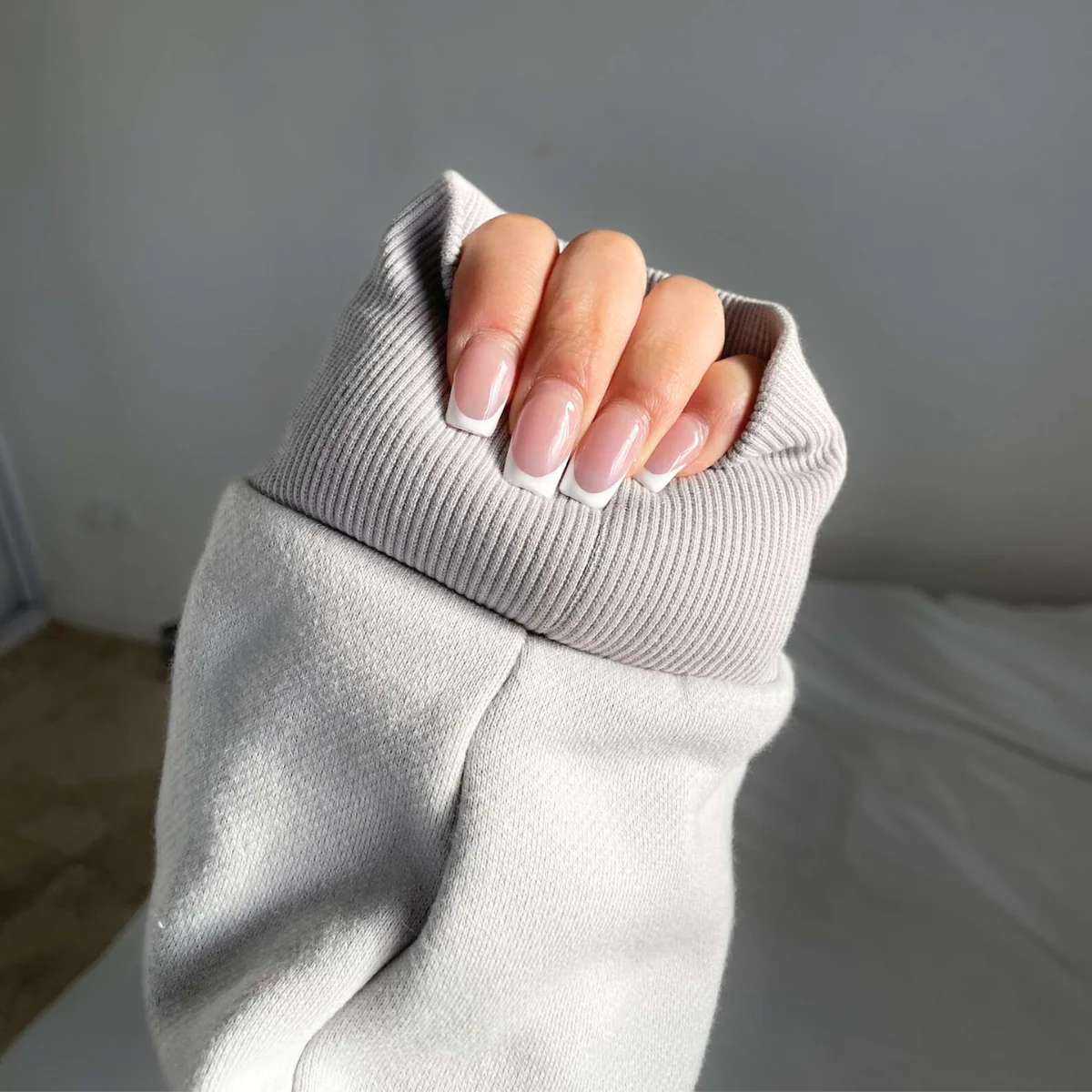 Women with manicured nails shows the padding at the wrist of a pale grey sweatshirt