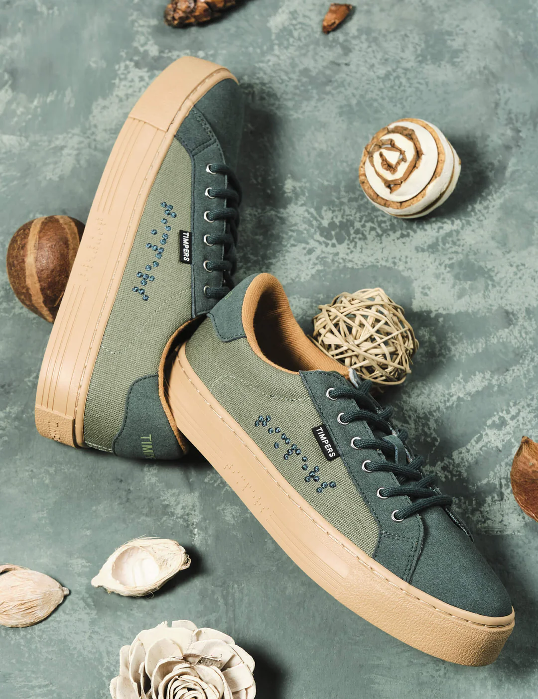 Dual colour green trainers on a grey background