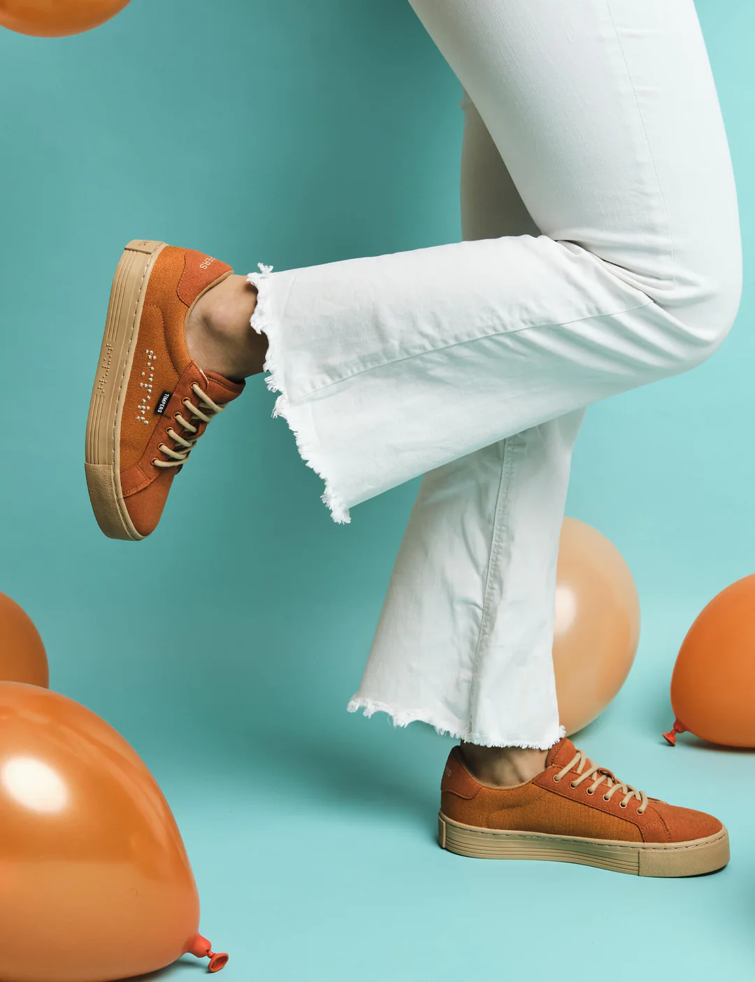 Brown timpers trainers worn by model on turquoise background